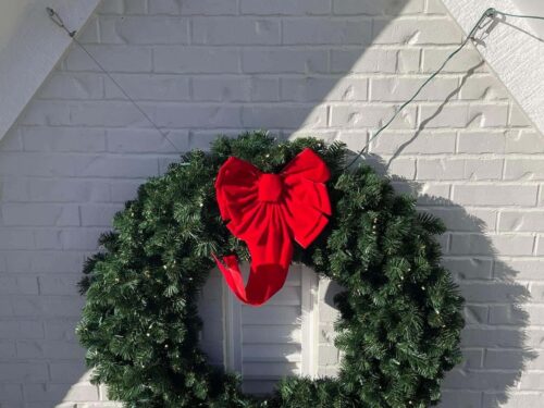 Wreath with red bow hanging against white wall